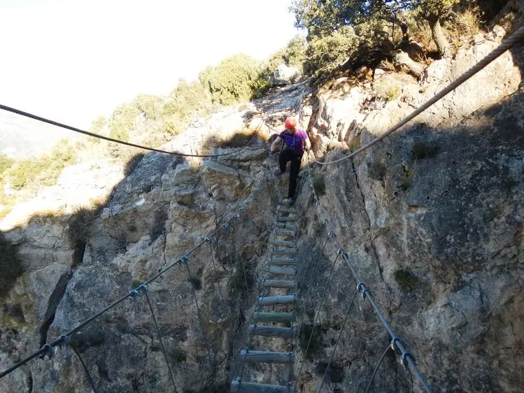 Interior de Castellón: hombre cruzando puente de cuerdas en un desfiladero